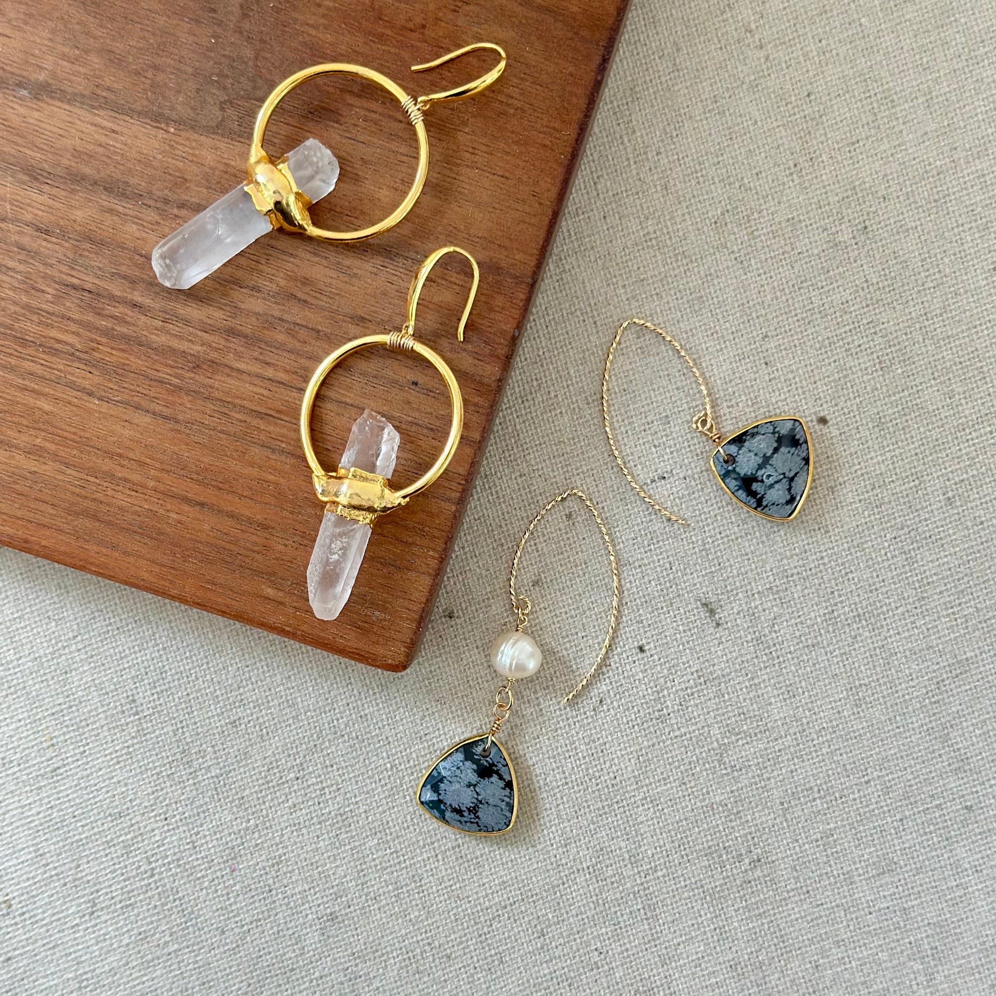 Gold earrings with crystal and stone elements on a wooden and stone surface